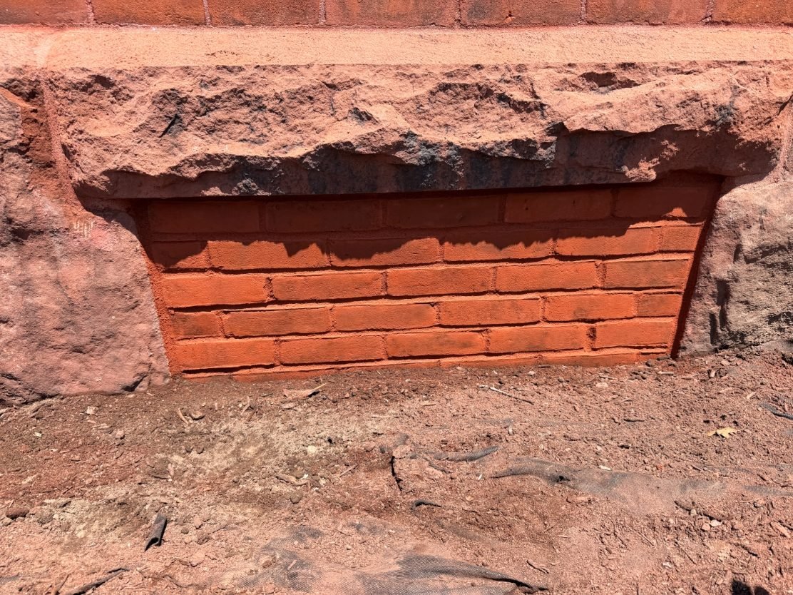 Restored brick foundation infill beneath a granite sill